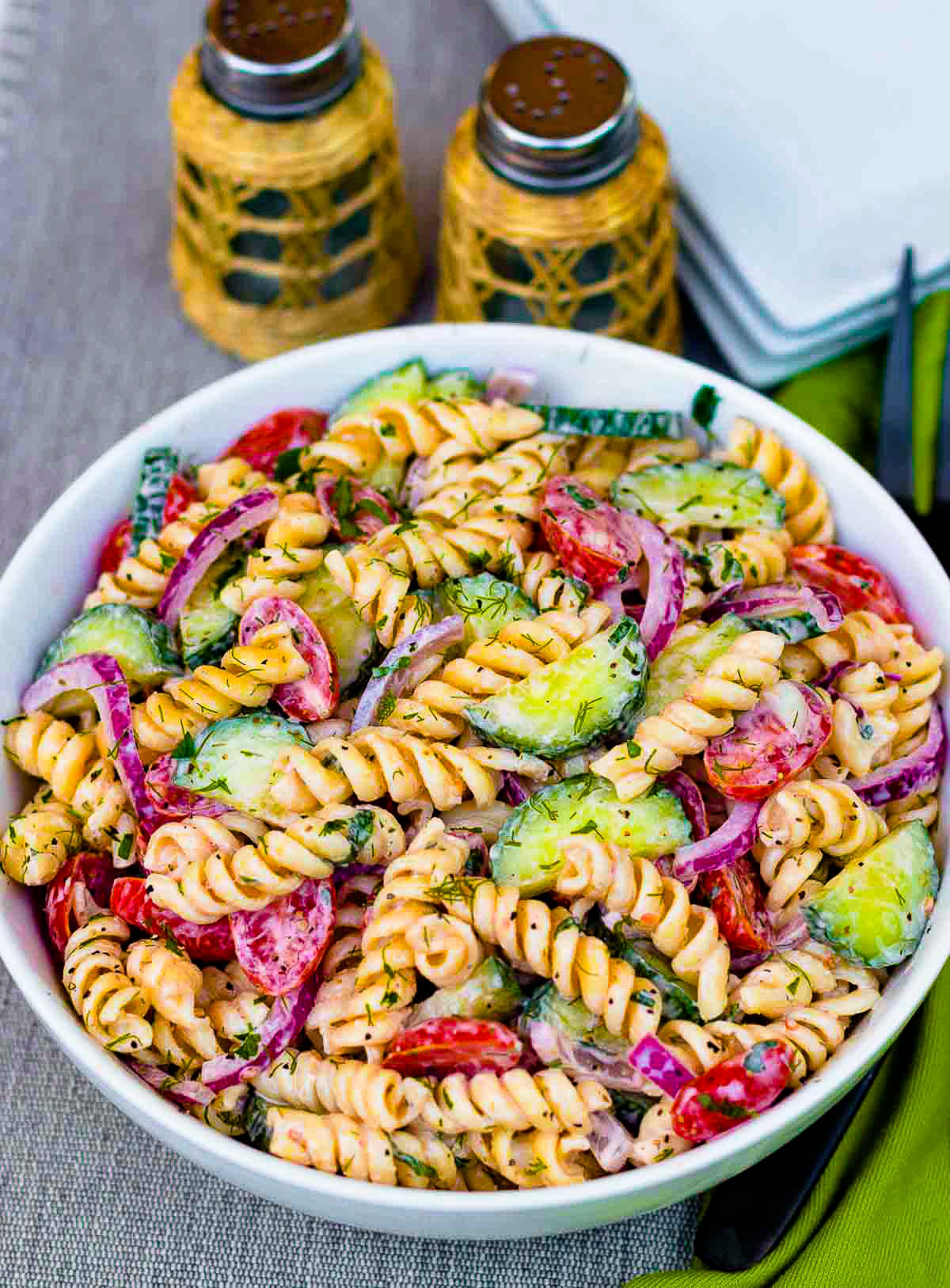 Creamy Tomato Cucumber Pasta Salad made with a simple dressing with fresh herbs and red onions.
