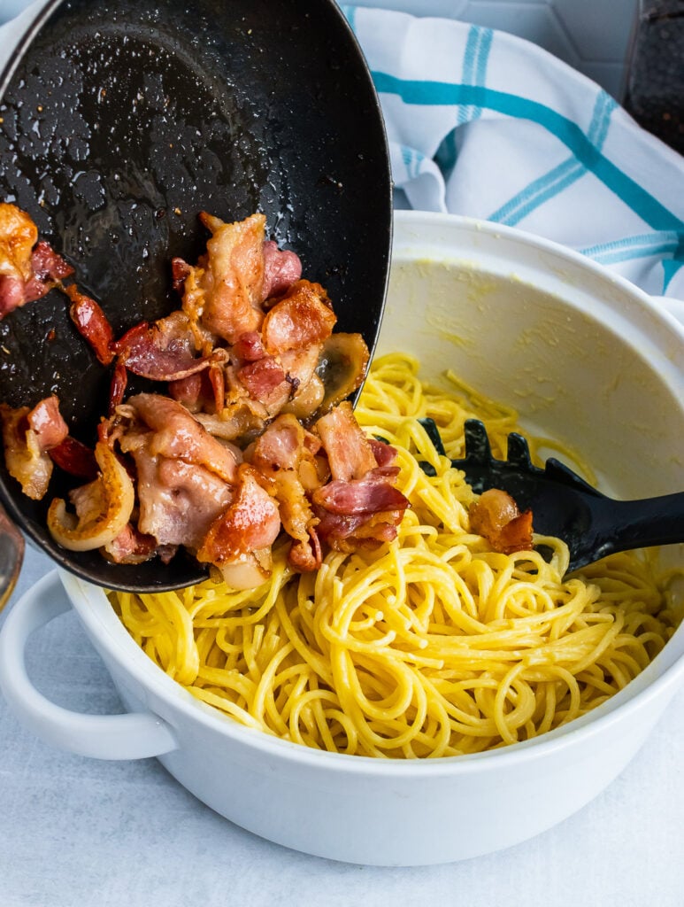 Pasta Carbonara with spaghetti and cooked bacon in a pot.