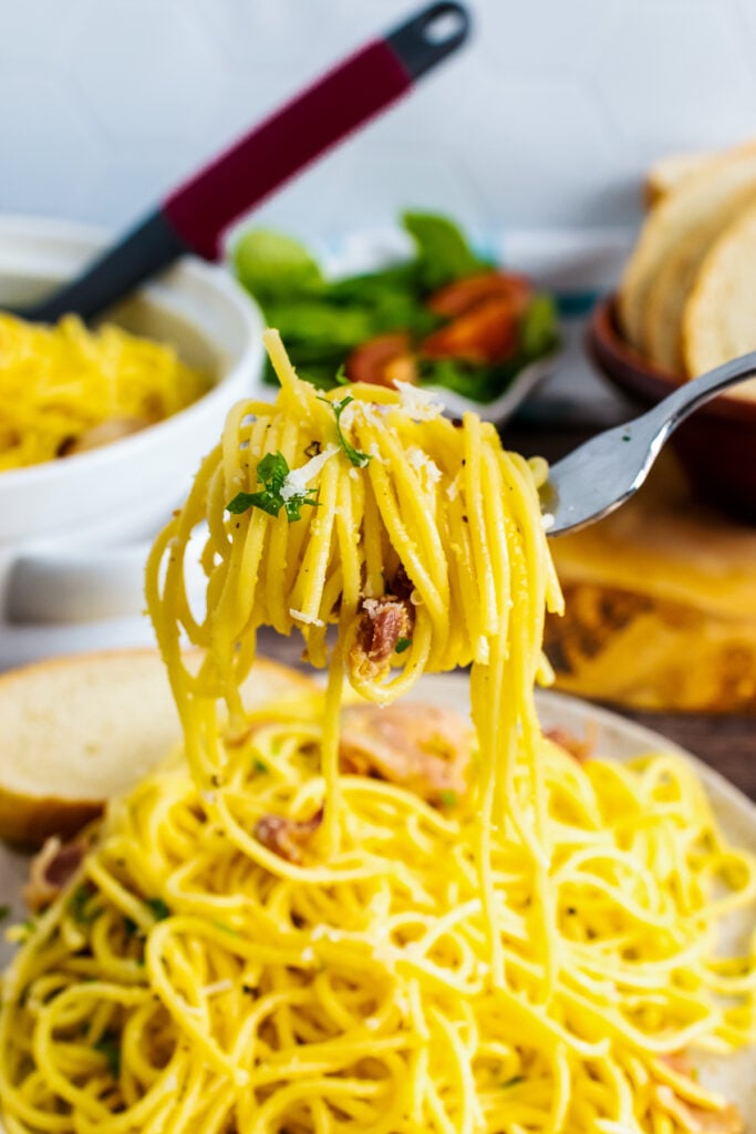 Pasta Carbonara on a fork with bacon and parsley garnigh