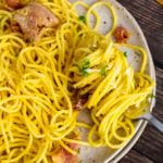 Pasta Carbonara on a plate twirled with a fork served with bread.