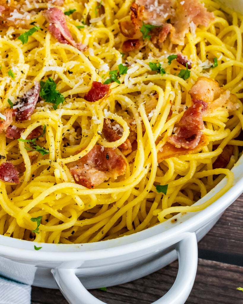 Pasta Carbonara in a white pot with bacon and cheese.