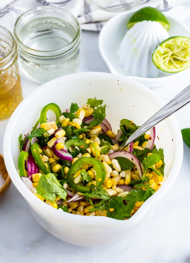 Corn, jalapenose, cilantro, jalapens mixed together in a whitle bowl for Pickled Corn.