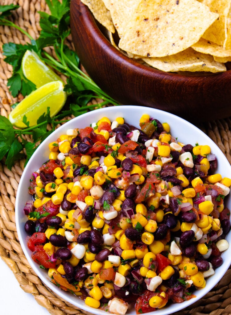 White bowl with black beans and corn salsa and brown bowl with tortilla chips.
