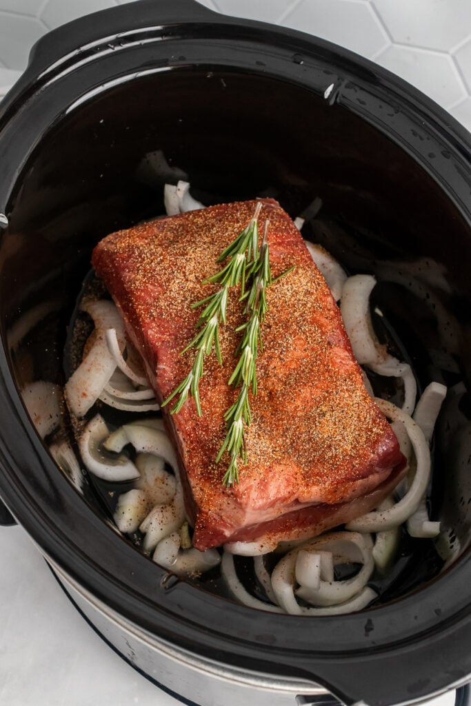 Pot Roast with onions, seasoning and rosemary in a crock pot.