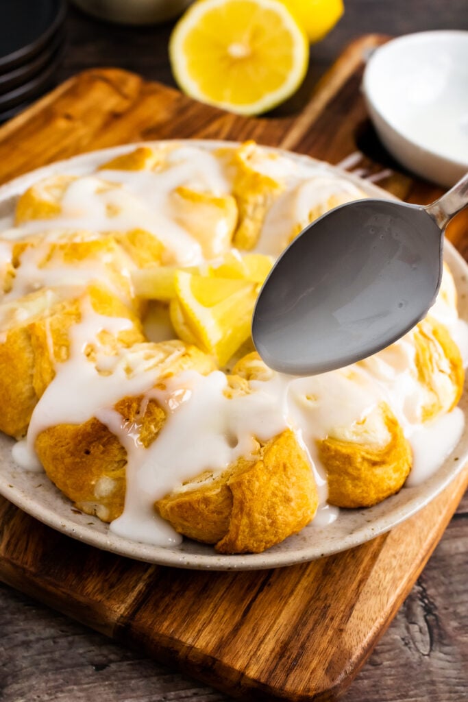 Baked cream cheese danish with lemon sugar icing drizzled with a spoon.
