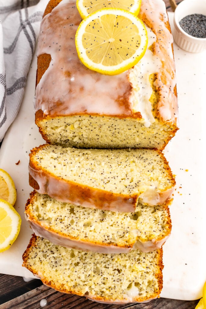 Loaf of Lemon Poppy Seed Cake sliced on a cutting board.