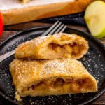 2 slices of Apple Strudle on a black plate with fork.