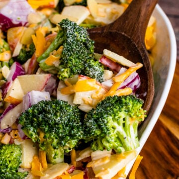 Broccoli Apple Salad with cheese and almonds on a wooden spoon.