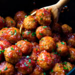 Bourbon Meatballs in a black pot with a wooden spoon