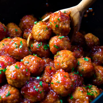 Bourbon Meatballs in a black pot with a wooden spoon