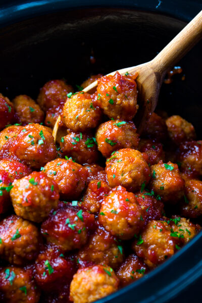 Bourbon Meatballs in a black pot with a wooden spoon