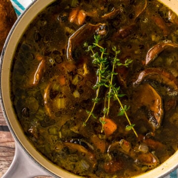 Gray stock pot with mushroom soup and fresh thyme.