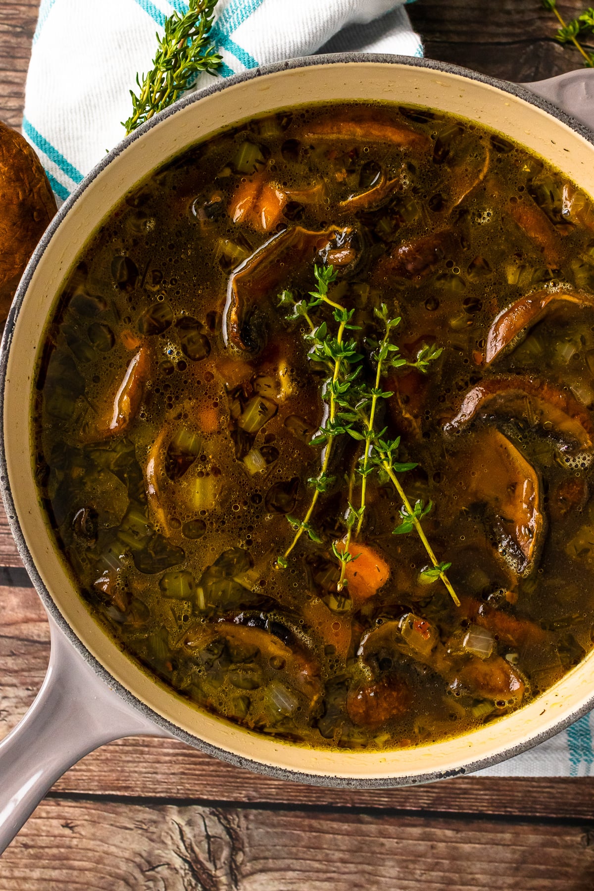 Gray stock pot with mushroom soup and fresh thyme.