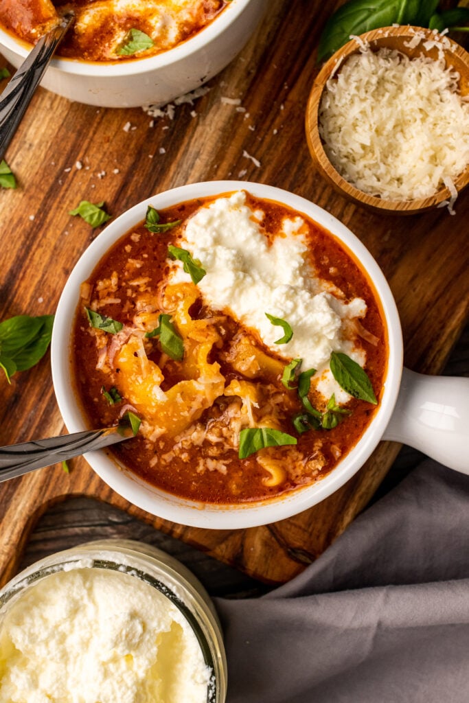 White soup bowl with Lasagna Soup topped with ricotta cheese.