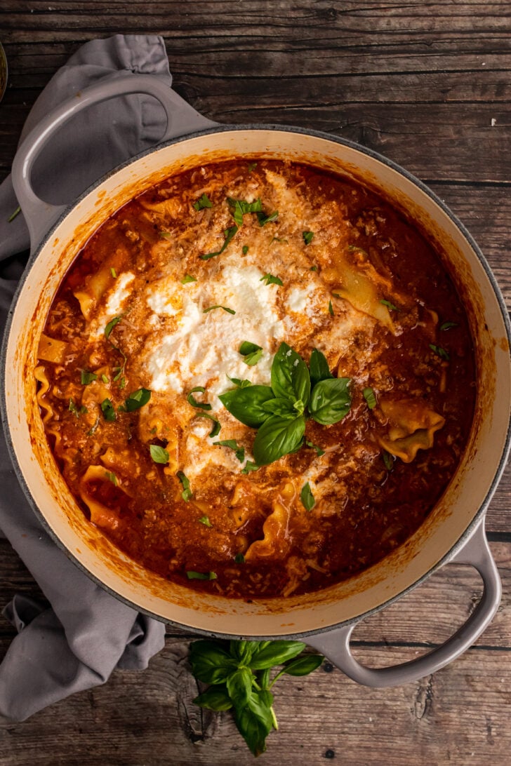 Gray stock pot with Lasagna Soup with ricotta cheese and fresh basil.