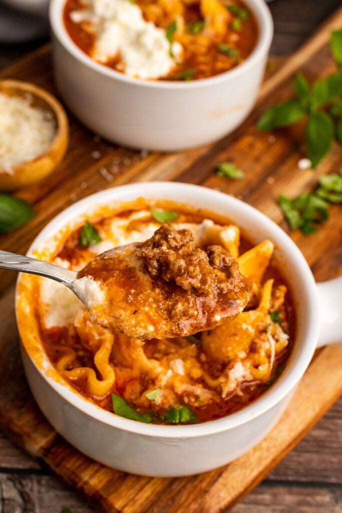 Lasagna Soup with ricotta cheese in a white pot on a spoon.