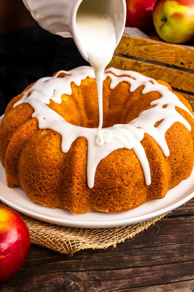 Pitcher with icing being poured over Apple Spice Cake.