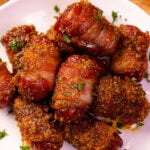 Sweet And Spicy Bacon Wrapped Little Smokies garnished with fresh parsley on a white plate, overhead view