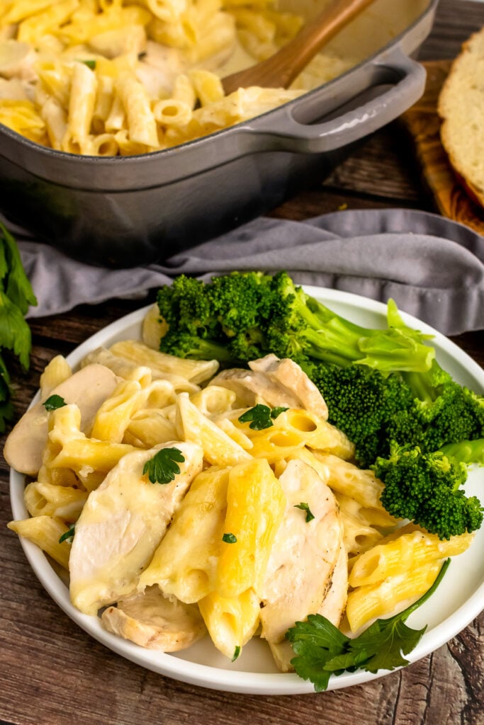 Chicken Alfredo Bake on a white plate with broccoli.