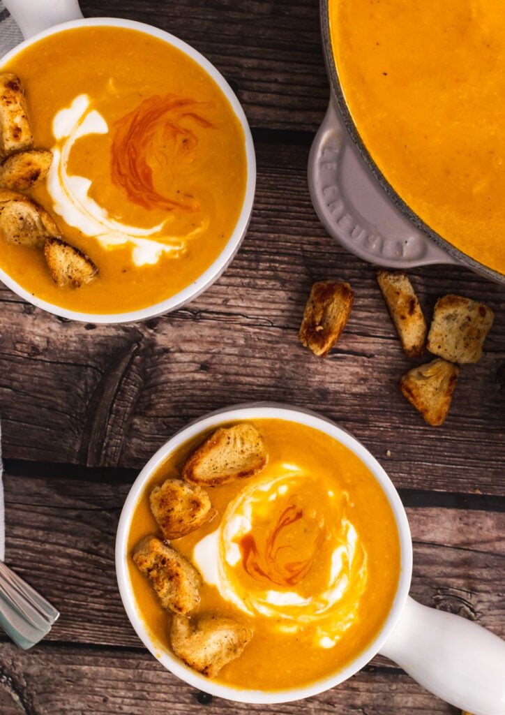 Two white bowls with Sweet Potato Soup topped with croutons.