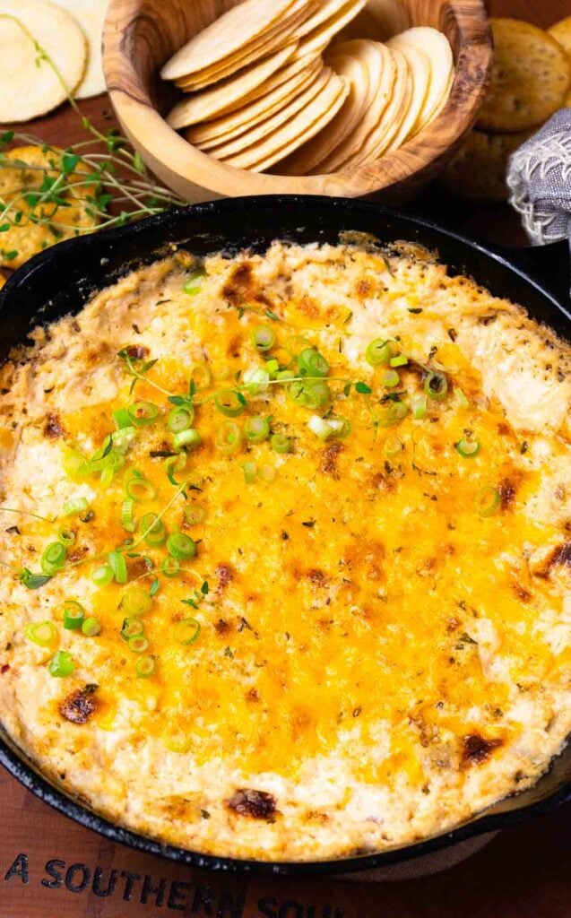 Cast iron cooked crab dip with green onions.