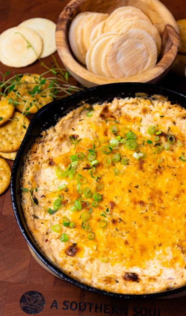 Cast iron cooked crab dip with green onions.