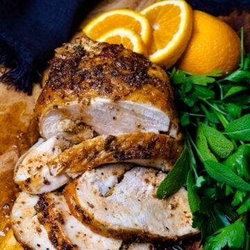 Air-Fryer Turkey Breast on a cutting board with herbs and oranges