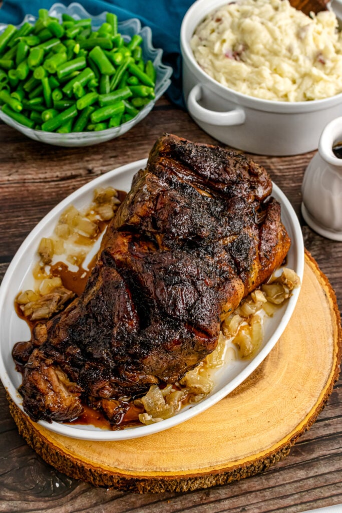 Balsamic Pork Roast on a serving platter with green beans and mashed potatoes.