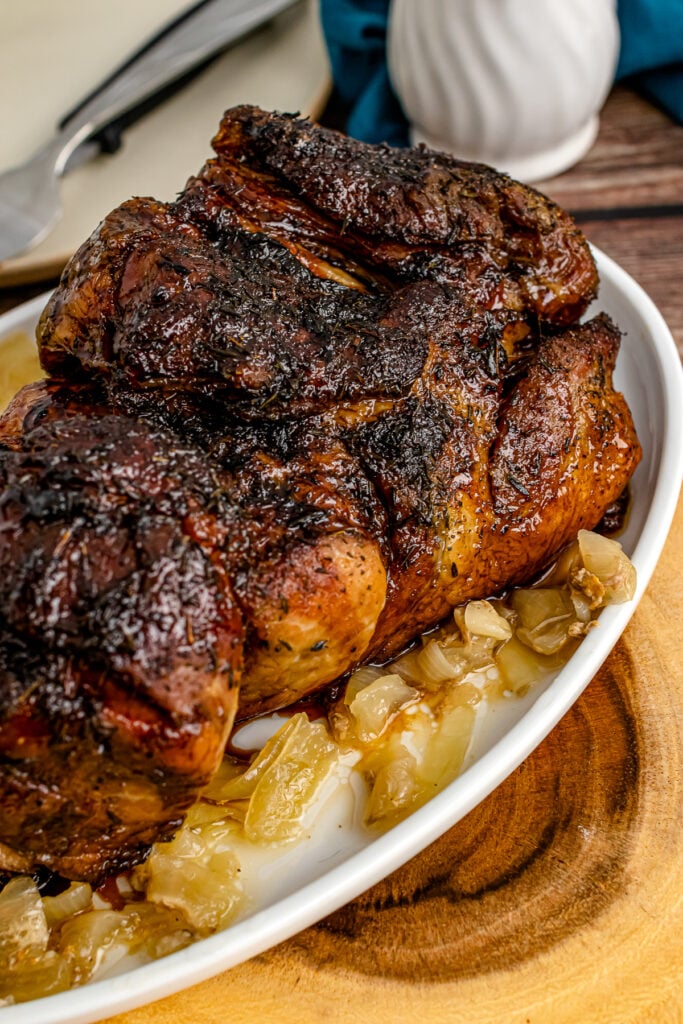 Balsamic Glazed Pork Roast iwith onion on a white serving platter.