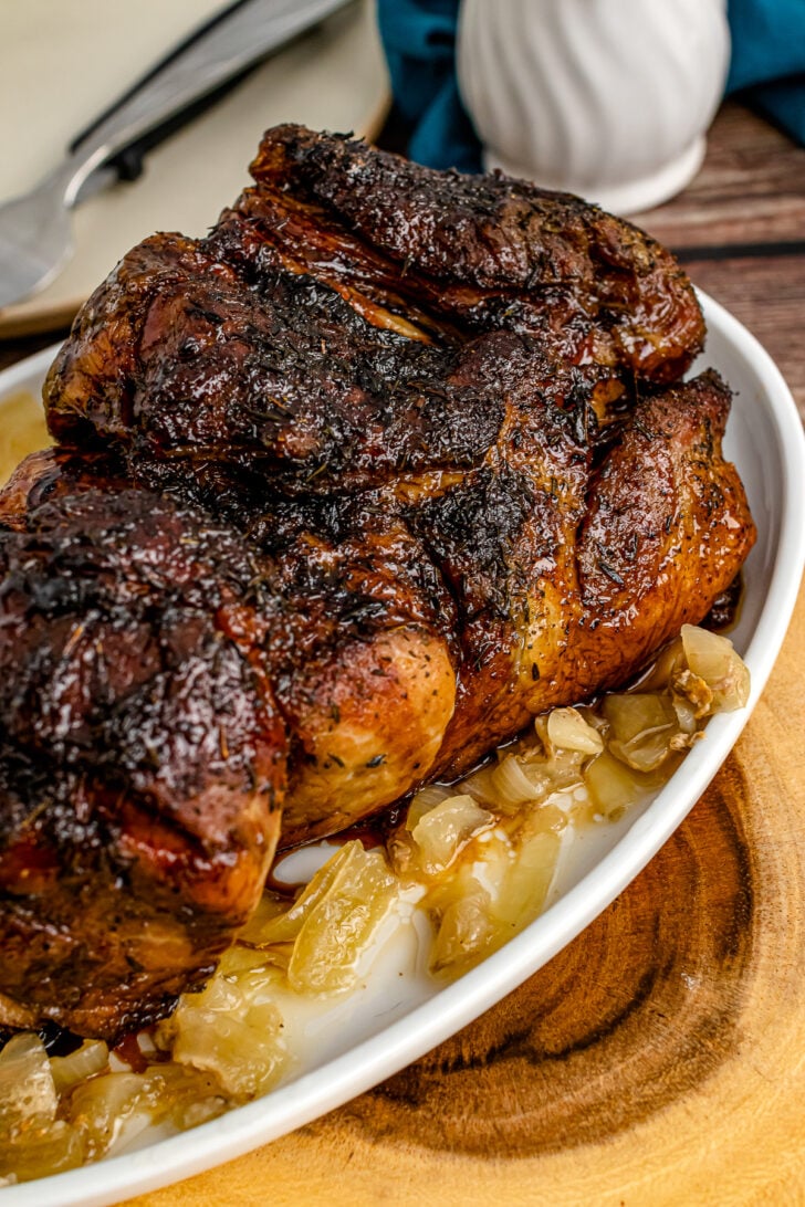 Balsamic Glazed Pork Roast iwith onion on a white serving platter.