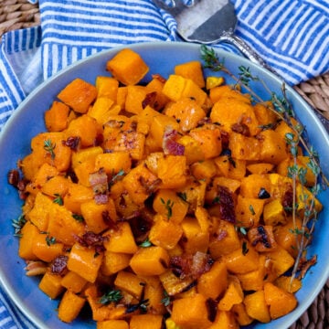 Blue bowl with roasted butternut squash with fresh thyme and a fork for serving.
