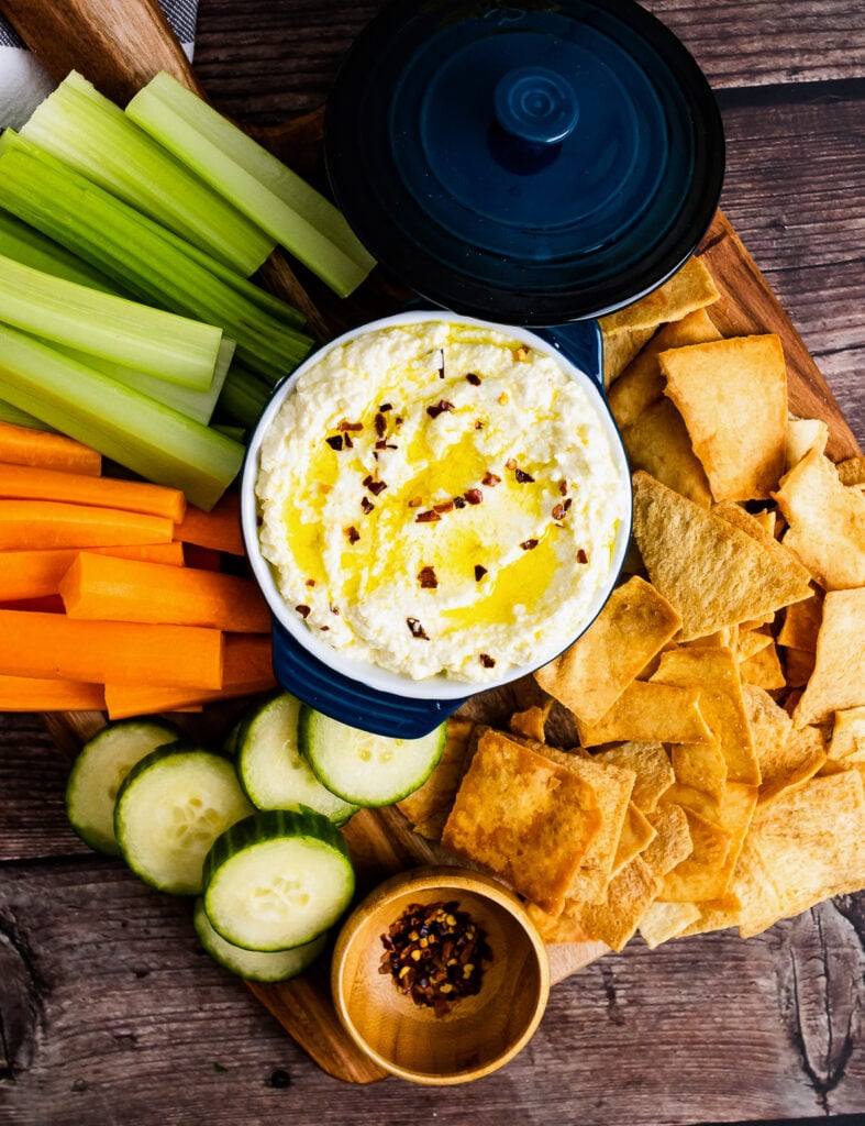 Wooden tray with whipped feta, veggies for dipping and crackers.