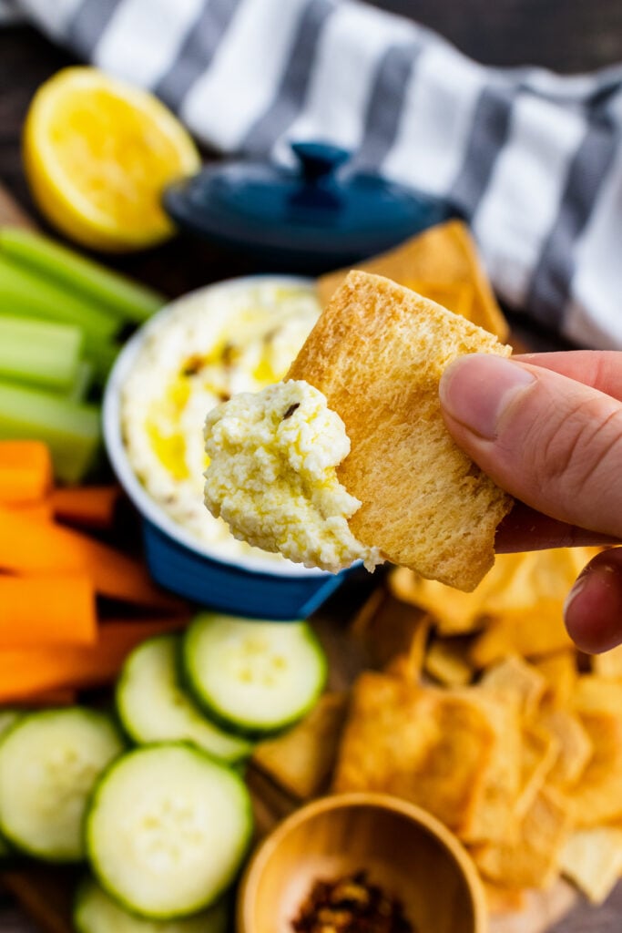 Hand holding cracker with Whipped Feta.