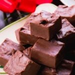 Mom's Homemade Fudge cut into squares on white plate with red flowers in background