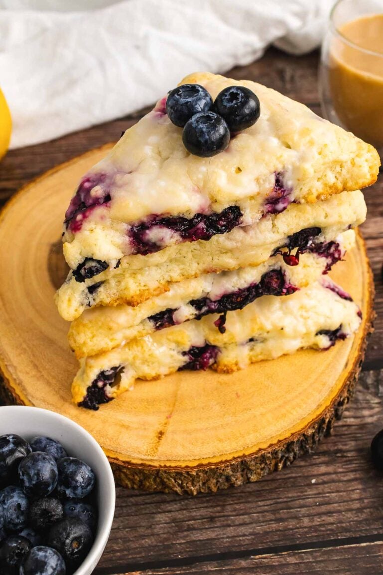 3 Blueberry Lemon Scones stacked on a wooden board served with coffee.