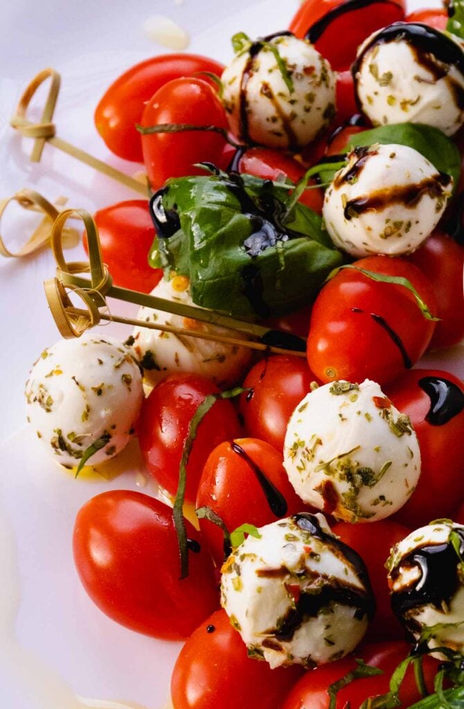 Tomatoes, mozzarella balls with Italian seasoning and basil for a holiday treat!