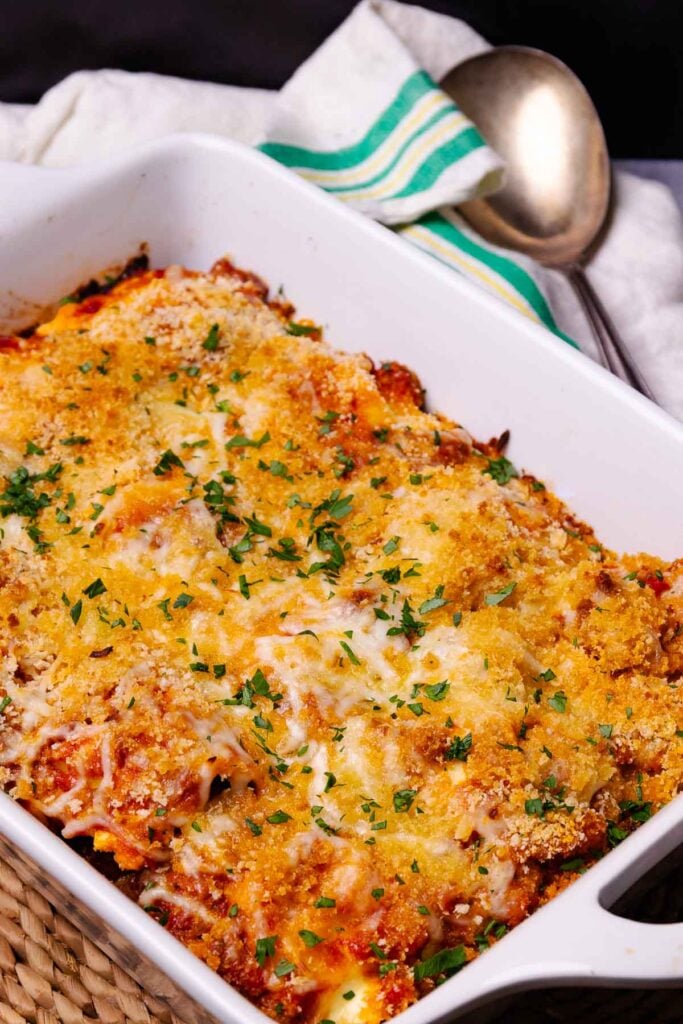 Cheesy Italian Sausage Ravioli Bake in a pan served with dinner.