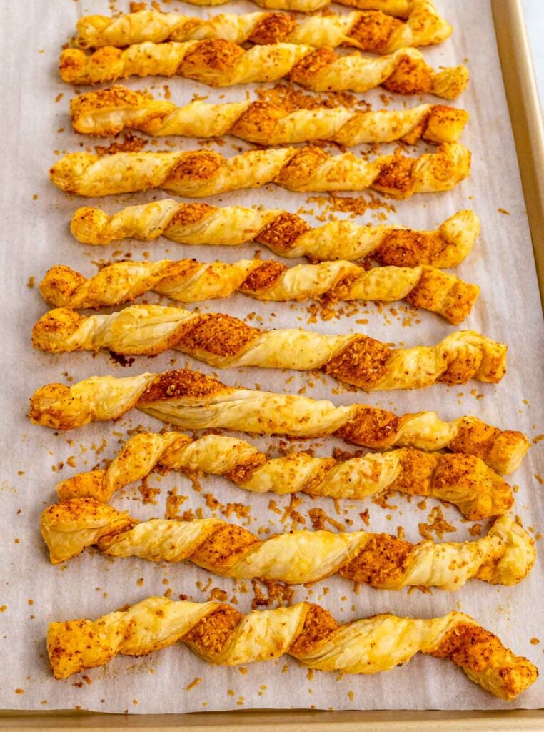Puffed Pastry Cheese Straws baked on a parchment lined baking sheet.