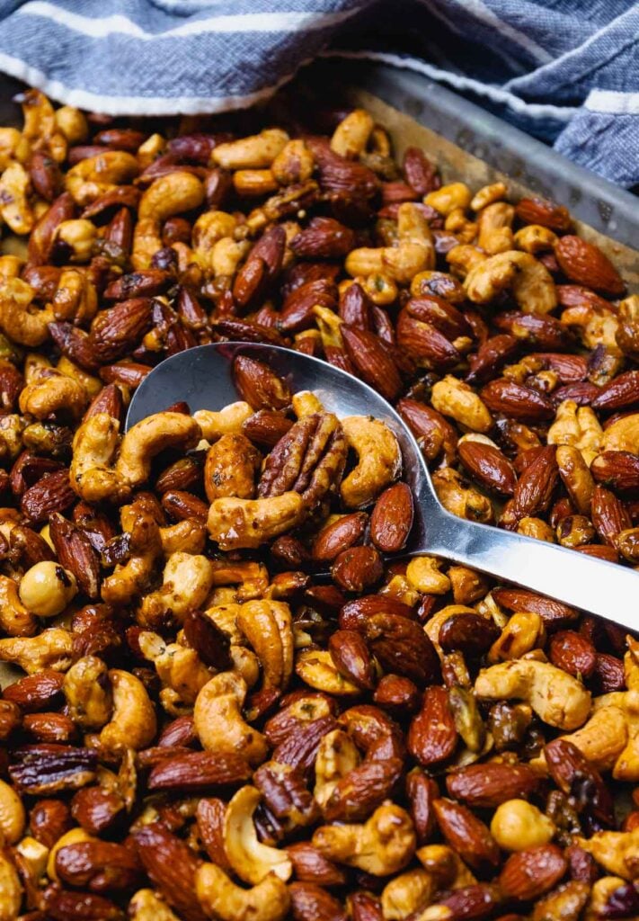 Spoonful of sweet and spicy roast nuts on a sheet pan.