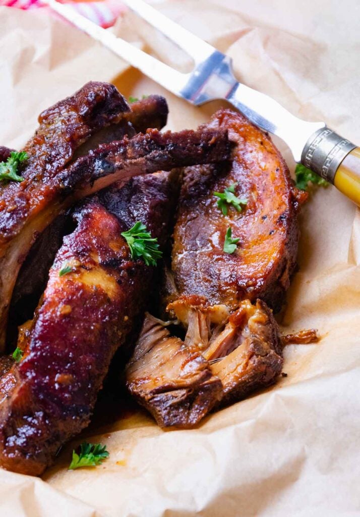 Platter full of Crock Pot Country Style Pork Ribs sprinkled with fresh parsley.