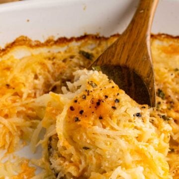 Wooden spoon serving cheesy hash brown casserole.