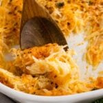 Wooden spoon with cheesy hash brown casserole.
