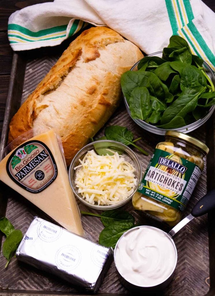 Ingredients for spinach artichoke bread all on a baking pan.