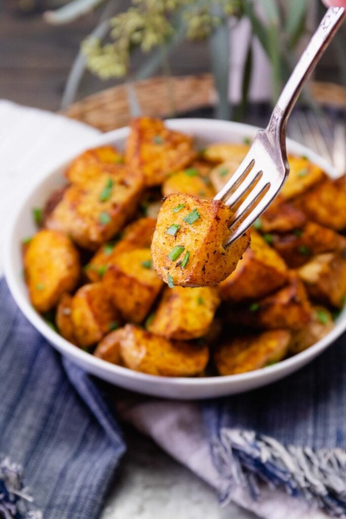 Fork holding air fryer cajun potatoes.