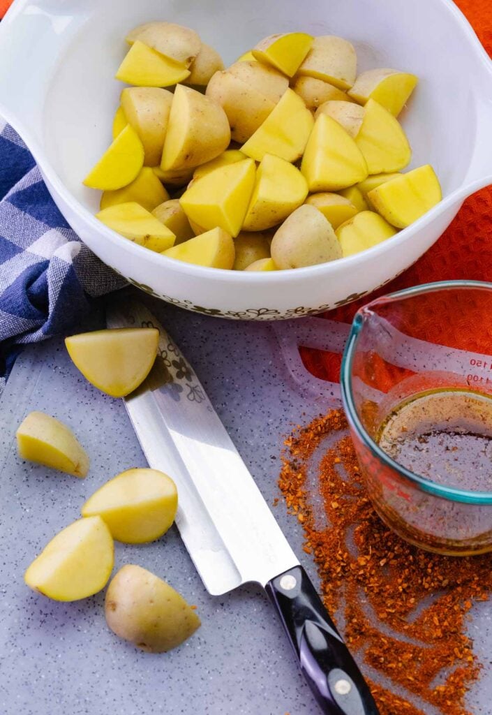 Diced potatoes with cajun seasoning mix on a cutting board.