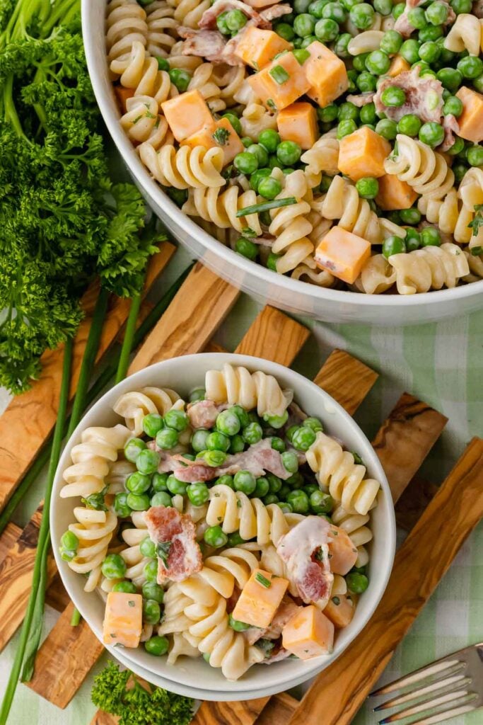 Large serving bowl with bacon ranch pasta salad along with small bowl and fork.