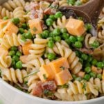 Bacon ranch pasta salad being tossed with a wooden spoon.