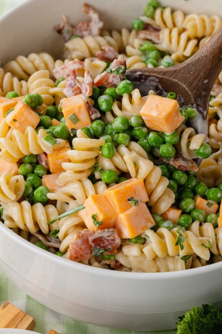 Bacon ranch pasta salad being tossed with a wooden spoon.