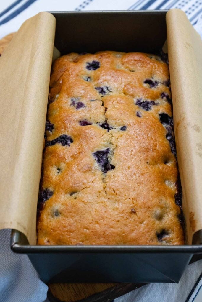 Blueberry bread in a loaf pan and parchment.