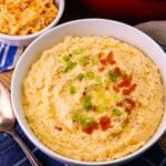 Big bowl of Pimento Cheese Grits topped with pimentos and sliced green onions.